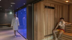 Una moderna spa con pannelli in legno, una parete divisoria in vetro e una panca.
