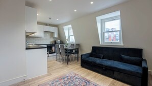 Un appartement moderne doté d’une cuisine, d’un coin repas et d’un canapé noir.