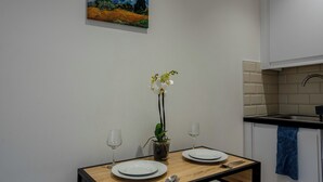 A dining area with a table set for two, a vase with flowers, and a painting on the wall. - Stylish and cozy flat (London)