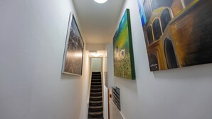 A hallway with a staircase leading to another room, decorated with framed pictures on the walls. - Stylish and cozy flat (London)