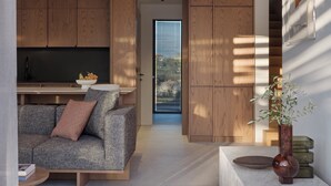 A modern living space with a sofa, a coffee table, wooden cabinets, and a vase with plants. - Noero Villas Lefkada (Lefkada)