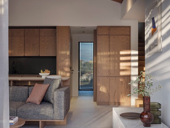 A modern living space with a sofa, a coffee table, wooden cabinets, and a vase with plants.
