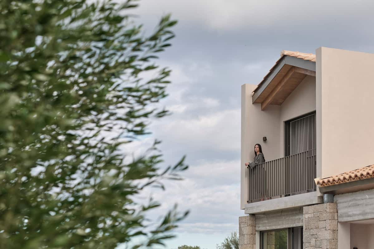 A modern building with a balcony, stone base, and a window.