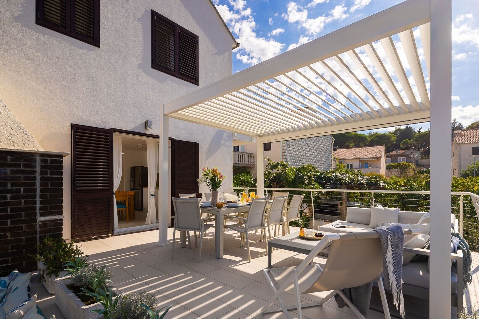 A covered outdoor patio with a dining table and chairs, a sofa, and a pergola.