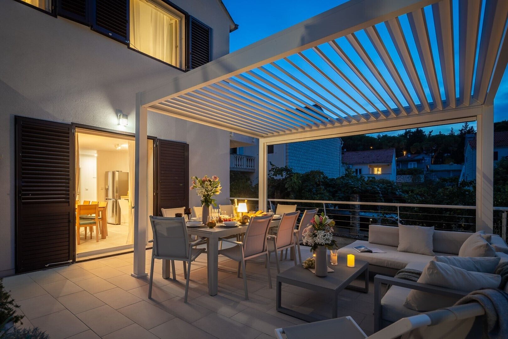 Un patio al aire libre con una mesa de comedor preparada para dos, sillas alrededor y un sofá.