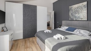 Un dormitorio moderno con una cama grande, un armario y un cuadro en la pared.