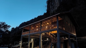 A wooden cabin with a balcony, surrounded by trees and a cliff. - Papaya Resort Nong Khiaw (Nong Khiaw)
