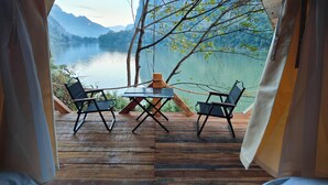 A wooden deck with a table and two chairs overlooking a lake with mountains in the background. - Papaya Resort Nong Khiaw (Nong Khiaw)