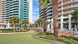 A resort with high-rise buildings, palm trees, and a well-maintained lawn.
