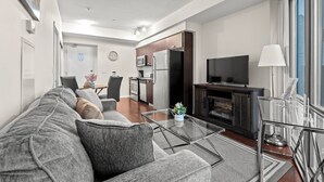 A modern living room with a sofa, coffee table, and a TV. There is a kitchen area with a refrigerator and microwave. - GLOBALSTAY Magnificent 1 Bedroom High Floor View (Toronto/Canada)