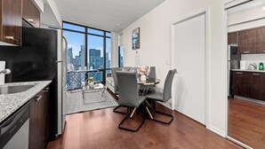 A modern kitchen with a built-in oven, a dining area with a glass table and chairs, and a view of the city skyline through large windows. - GLOBALSTAY Magnificent 1 Bedroom High Floor View (Toronto/Canada)