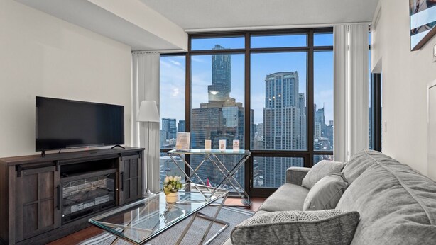 A modern living room with a large TV, a fireplace, a glass table, and a sofa. - GLOBALSTAY Magnificent 1 Bedroom High Floor View (Toronto/Canada)