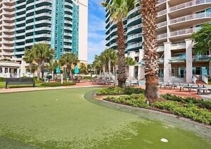 Een resort met hoge gebouwen, palmbomen en een verzorgd gazon.