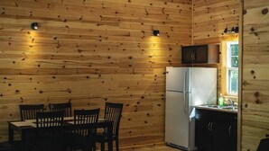 A compact kitchen with a built-in refrigerator, wooden walls, and a small window. - Pike's Place Cabin - Lakewood Park Cabins (Kenora, Unorganized)