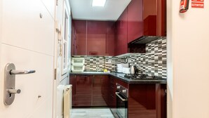 Una cocina moderna con armarios rojo oscuro, salpicadero a cuadros y electrodomésticos de acero inoxidable.