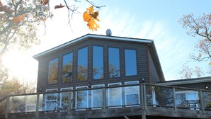 A two-story wooden house with a balcony and large windows.