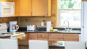 A kitchen with wooden cabinets, a microwave, a stove, and a window providing natural light.