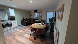 A modern kitchen with a built-in oven and microwave, a dining area with a round wooden table and chairs, and a large window providing natural light. - Petfriendly 1bedapt - 5 Min From Beach Aberdeen (Aberdeen)