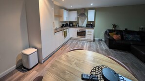 A modern kitchen with white cabinets, a built-in oven, and a dining area with a wooden table and chairs. - Petfriendly 1bedapt - 5 Min From Beach Aberdeen (Aberdeen)