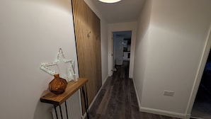 A hallway with a wooden floor, a white radiator, a star-shaped light fixture, and a wooden panel wall. - Petfriendly 1bedapt - 5 Min From Beach Aberdeen (Aberdeen)