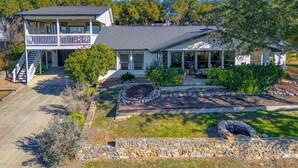 A two-story house with a covered porch and a stone fire pit. - Hot Tub + Games + Mini Golf | Open Labor Day! (Canyon Lake)