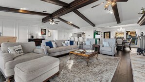 A spacious living room with a large sectional sofa, a coffee table, and a chandelier. - Hot Tub + Games + Mini Golf | Open Labor Day! (Canyon Lake)