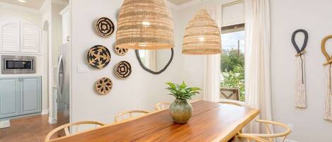 A dining area with a wooden table, wicker chairs, and pendant lights.