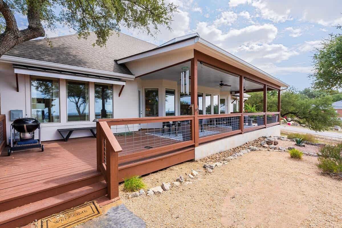 Une maison moderne dotée d’un porche abrité, de grandes fenêtres et d’un barbecue.