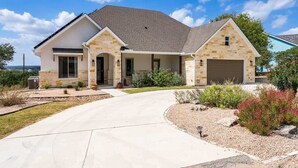 A two-story house with a stone facade, a garage, and a landscaped driveway. - Lake Views, Fire Pit, BBQ & Patio | Pet-Friendly! (Canyon Lake)