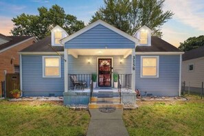 Une maison à deux étages avec un porche à l’avant, un petit hall d’entrée et une boîte aux lettres bien visible.