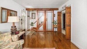 A spacious living room with hardwood flooring, a sofa, a lamp, and a staircase leading to another room.