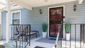 A residential house with a front porch, a black metal railing, and a door with a decorative glass panel.