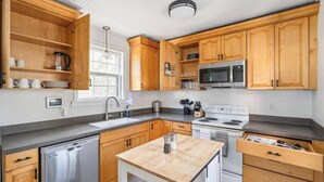 Uma cozinha moderna com armários de madeira, eletrodomésticos de aço inoxidável e uma ilha central.