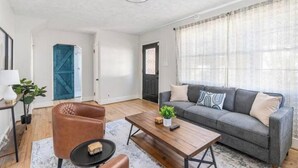 Uma sala de estar moderna com um sofá cinzento, uma mesa de centro de madeira e uma poltrona de couro castanho.