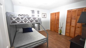A bunk bed with a patterned headboard, a bedside table, a lamp, and a wooden floor. - Nice 2 Bedroom Duplex Great For Contractors (Saint Mary's)
