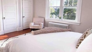 A bedroom with a bed, a chair, and a window.