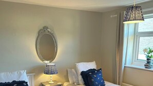 A hotel room with two beds, a bedside table with a lamp, a mirror, and a window with a view. - Peak District - 2 Beds - Sleeps 4 - Pet Friendly (Chesterfield)