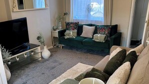 A living room with a sofa, a TV, a lamp, and a window with curtains. - Peak District - 2 Beds - Sleeps 4 - Pet Friendly (Chesterfield)