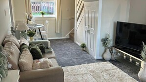 A living room with a sofa, TV, and a staircase. - Peak District - 2 Beds - Sleeps 4 - Pet Friendly (Chesterfield)