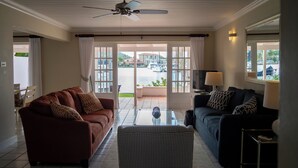 Ein Wohnzimmer mit einem braunen Sofa, einem blauen Sofa, einem Glastisch und einem Deckenventilator.