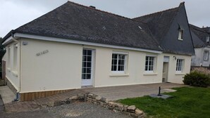 Een gebouw met twee verdiepingen, een schuin dak, een grindpad en een stenen muur.