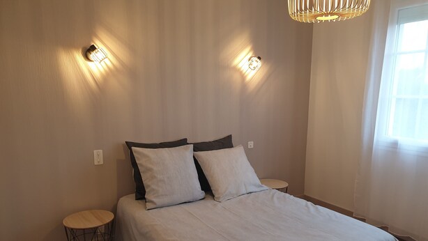 Een slaapkamer met een bed, twee nachtkastjes en een hanglamp.