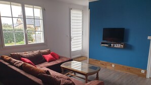 Een woonkamer met een bruine bank, een glazen salontafel en een blauwe accentmuur.