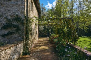 Un edificio de piedra con un sendero de jardín que conduce a un portón de madera.