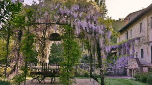 A garden with a wooden bench, a table, and a hanging light fixture. - Villa Mandorla by My Villa Collection (Barberino Tavarnelle)