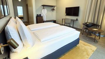 Una habitación de hotel con una cama grande, una mesita de noche, una lámpara y un televisor en la pared.