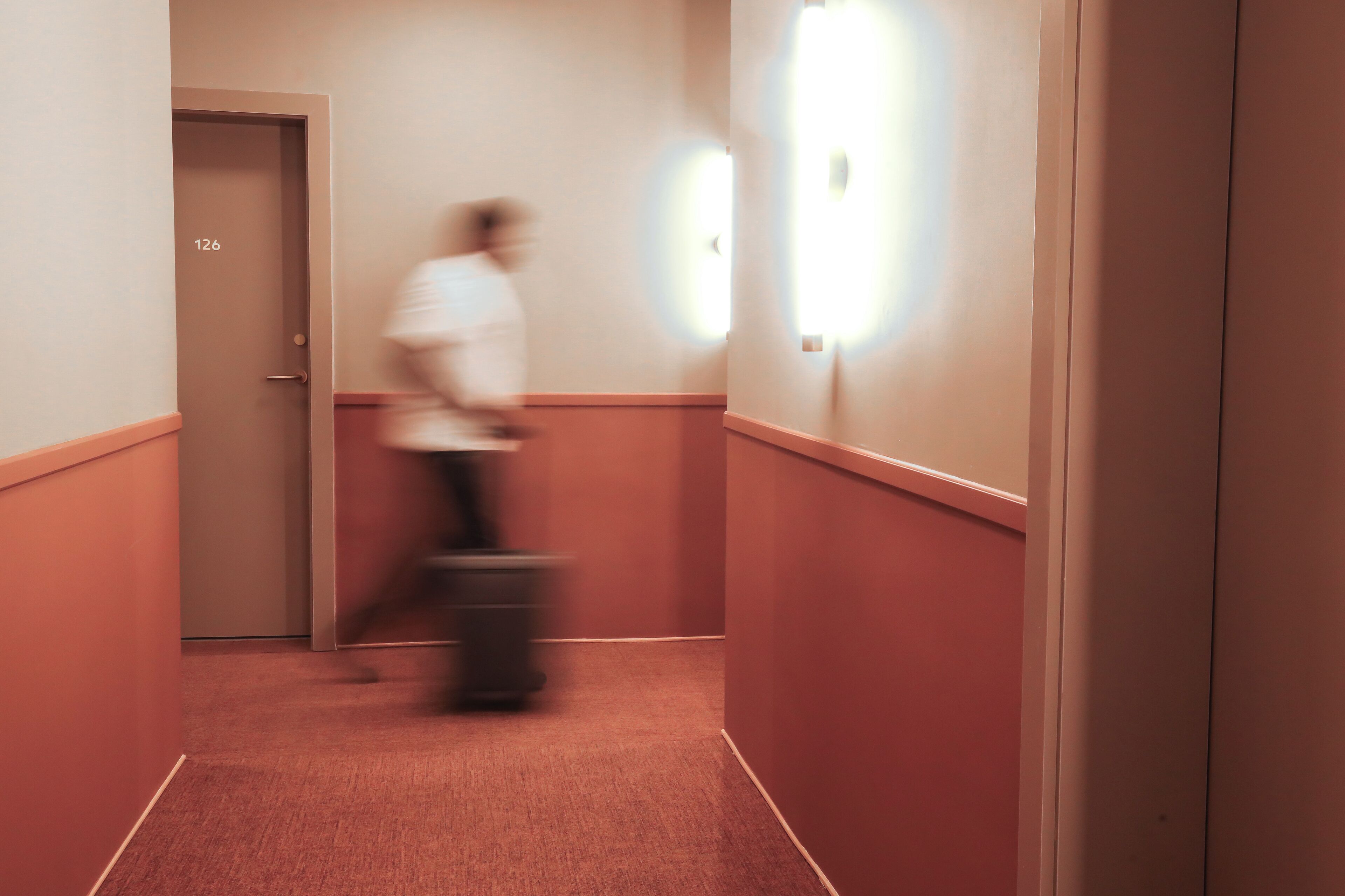 A corridor with a door labeled 126, a trash bin, and a wall-mounted light fixture.