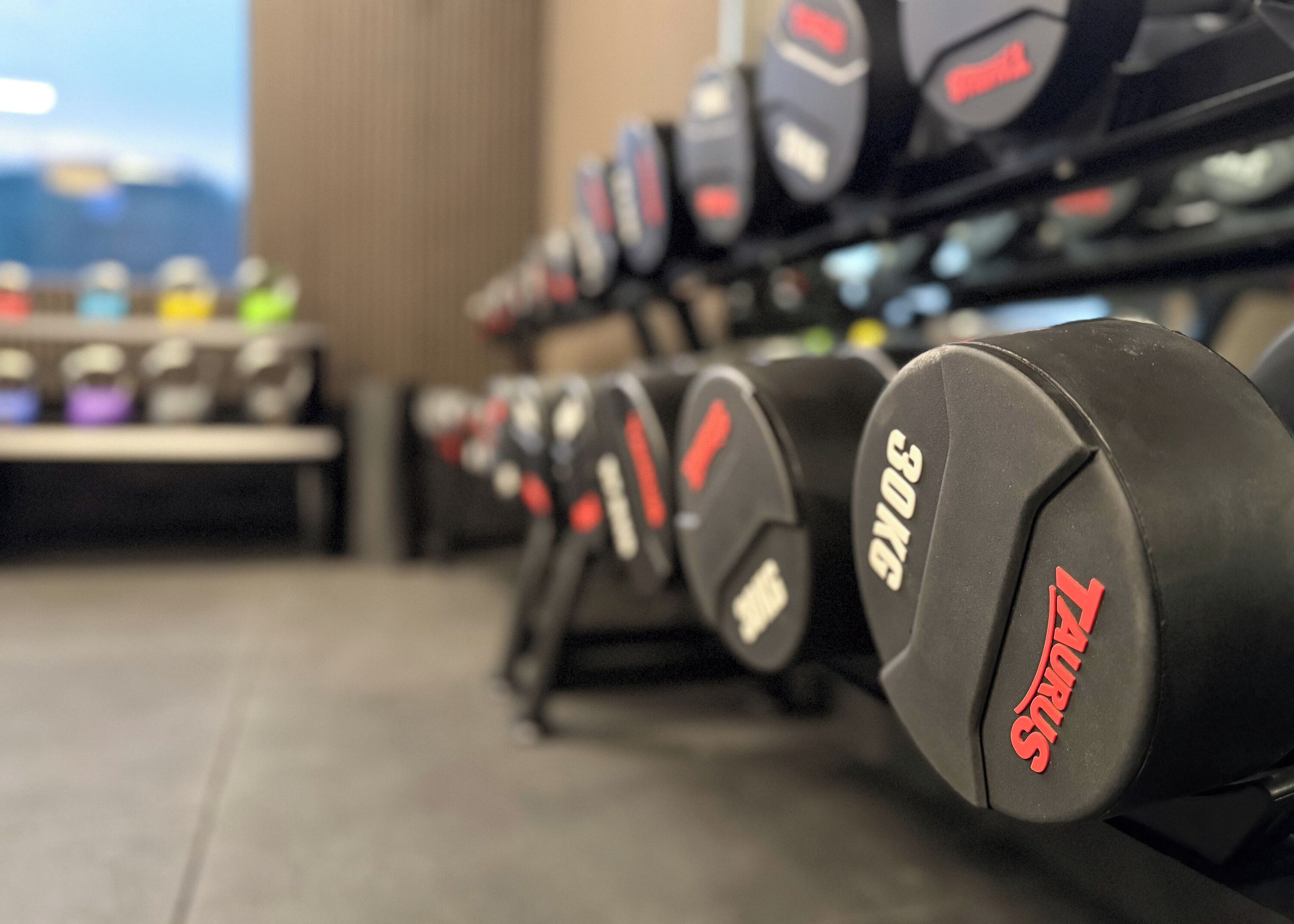 Una hilera de mancuernas con la marca "ZUMPH", ubicadas en un soporte en un gimnasio.