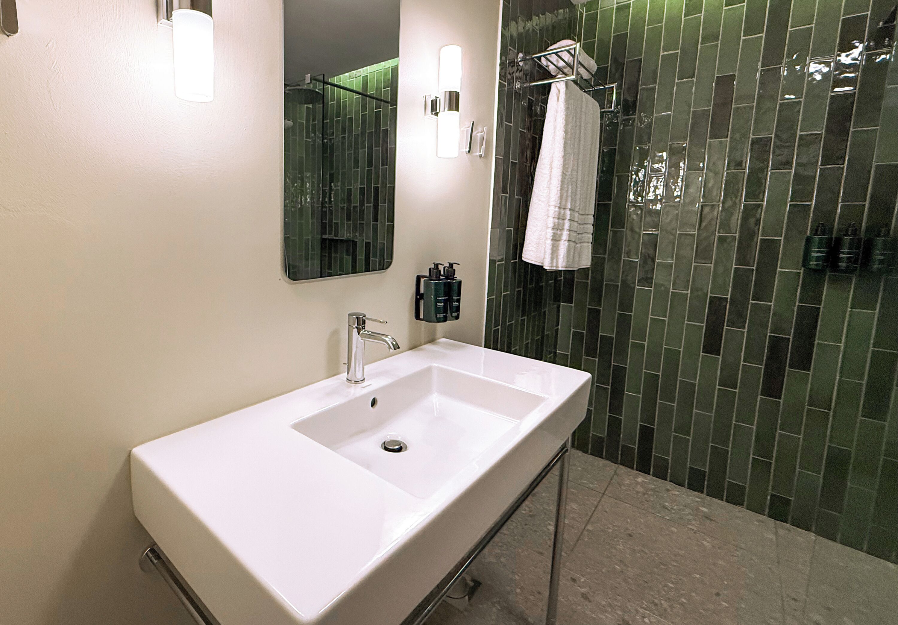 A bathroom with a white sink, a mirror, and a glass shower enclosure.