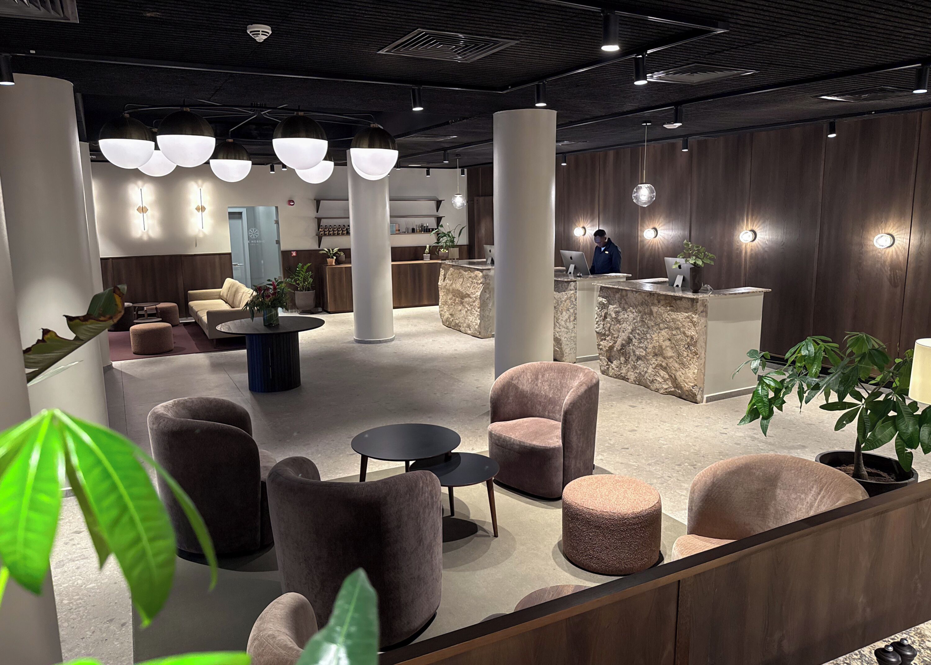 Eine moderne Lobby mit Sitzbereichen, einem Empfangsbereich und dekorativer Beleuchtung.